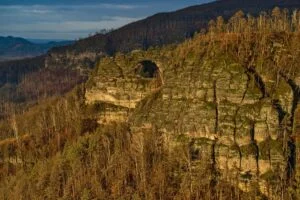 Pískovcová Pravčická brána ve skalní stěně nad lesy Českého Švýcarska