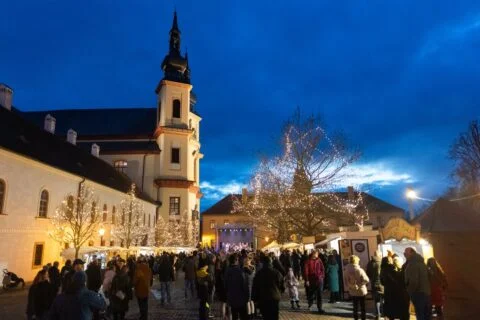 Adventní trh na Zámeckém návrší v Litomyšli za soumraku, v pozadí piaristický chrám